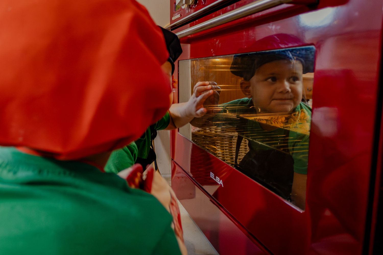 Child reflected in the oven door while baking